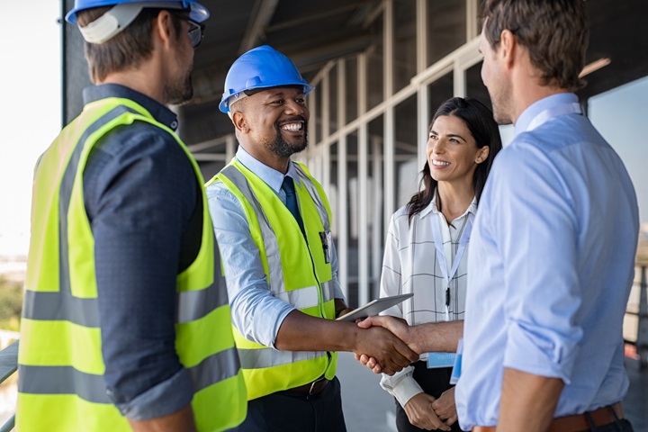 Four people standing together, two shaking hands