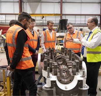 Nick Ahrens and academy visitors in a factory