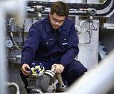 Engineer kneeling for pump inspection.